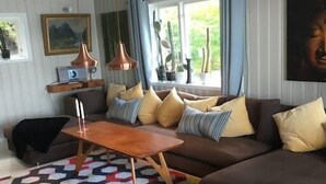 En moderne stue med en brun sofa, et træ sofabord og en farverig, geometrisk måtte.