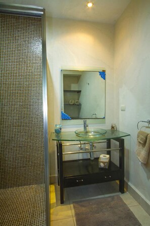 A bathroom with a glass sink, a mirror, and a shower area. - Apartamento PlayaDelCarmen 489 by Sinbad (Playa del Carmen)