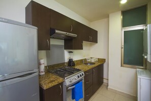 A kitchen with a stove, oven, and refrigerator, equipped with a gas range and a built-in microwave. - Apartamento PlayaDelCarmen 489 by Sinbad (Playa del Carmen)