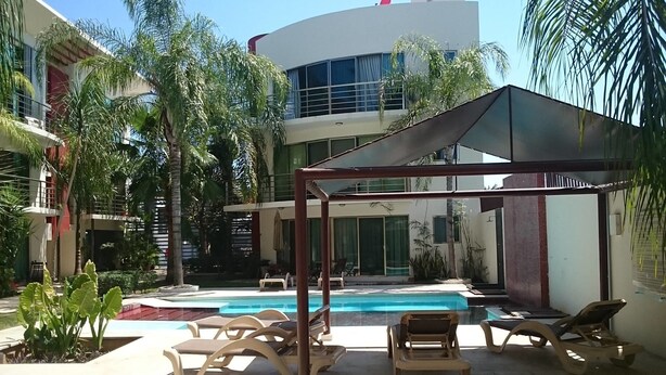 A pool area with lounge chairs and a shaded structure. - Apartamento PlayaDelCarmen 489 by Sinbad (Playa del Carmen)