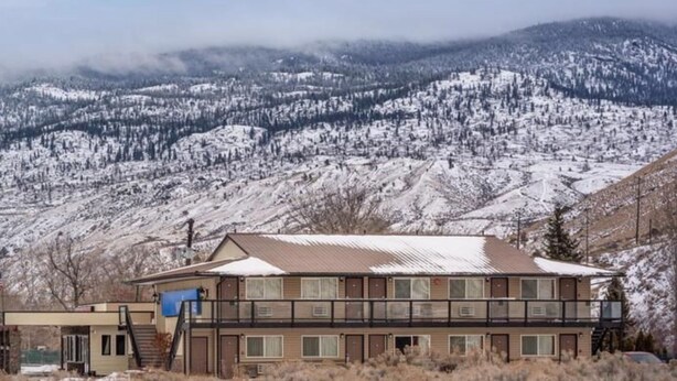 A two-story building with a flat roof, multiple windows, and a visible staircase leading to the upper floor. - Riverside Motel (Cache Creek)