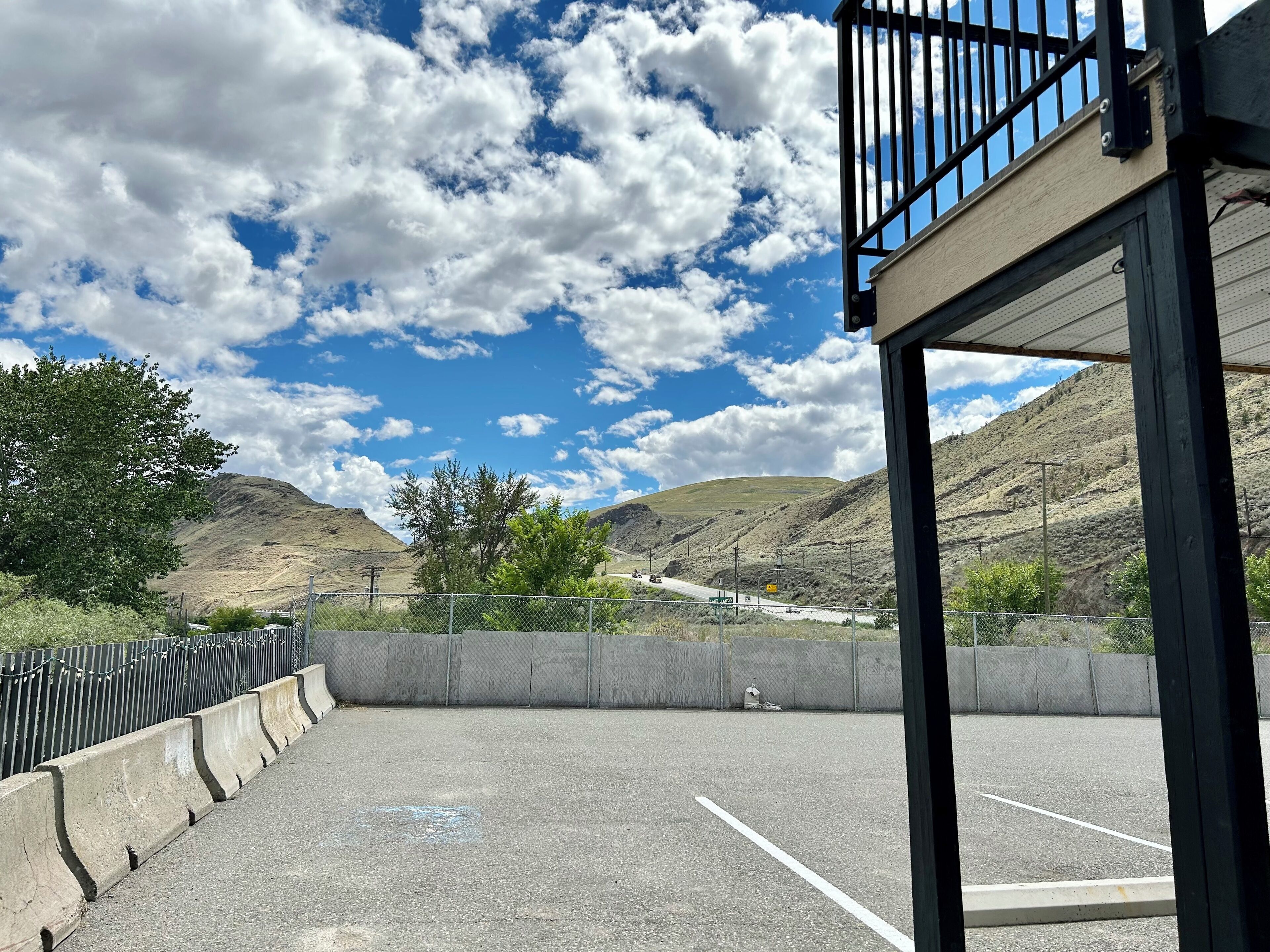 An outdoor parking area with a clear view of a mountainous landscape under a partly cloudy sky.