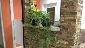 A stone wall with plants and a door to a room. - Riverside Motel (Cache Creek)