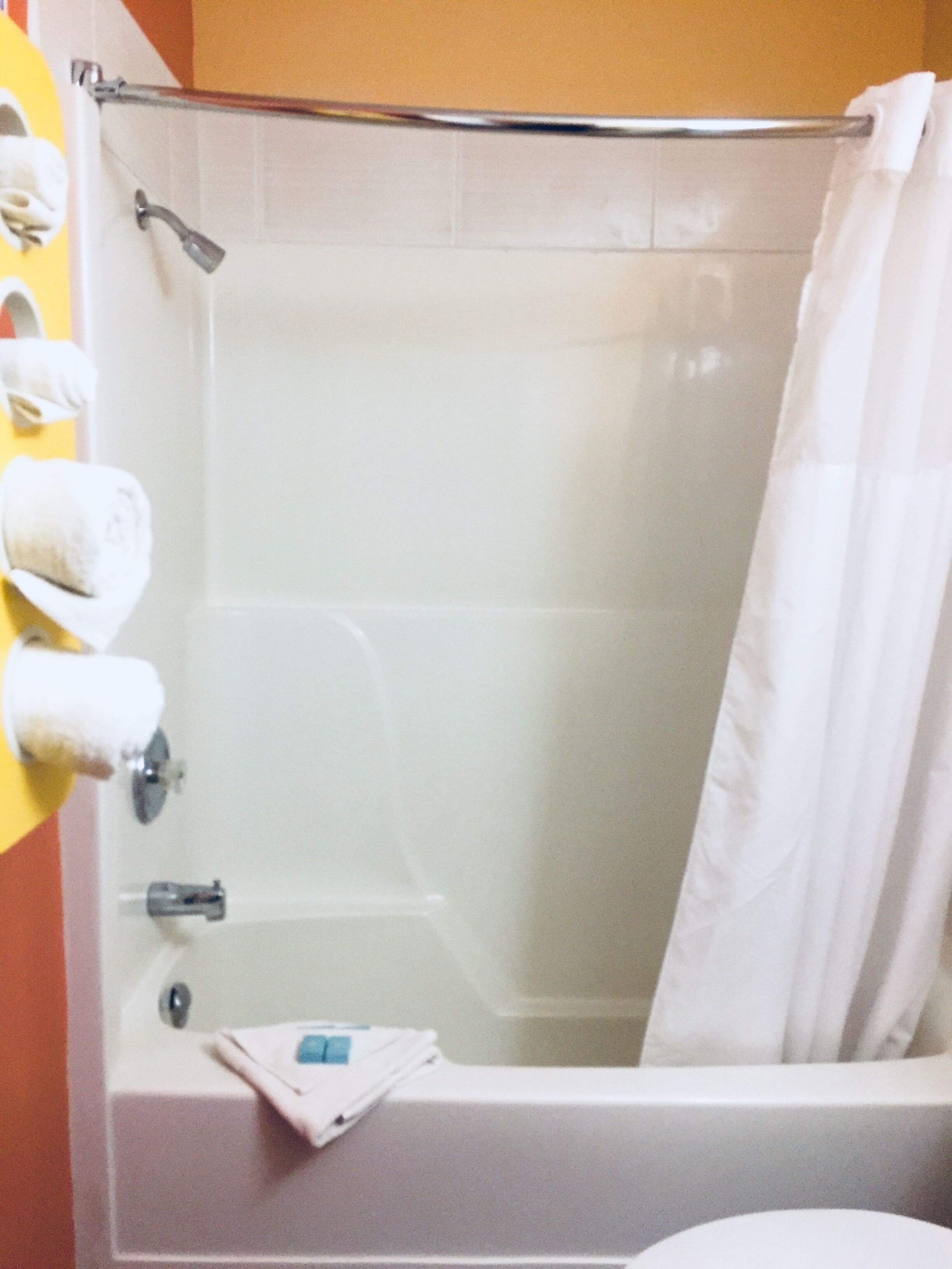 A bathroom with a bathtub, a shower, and a toilet. There are towels hanging on a rack.