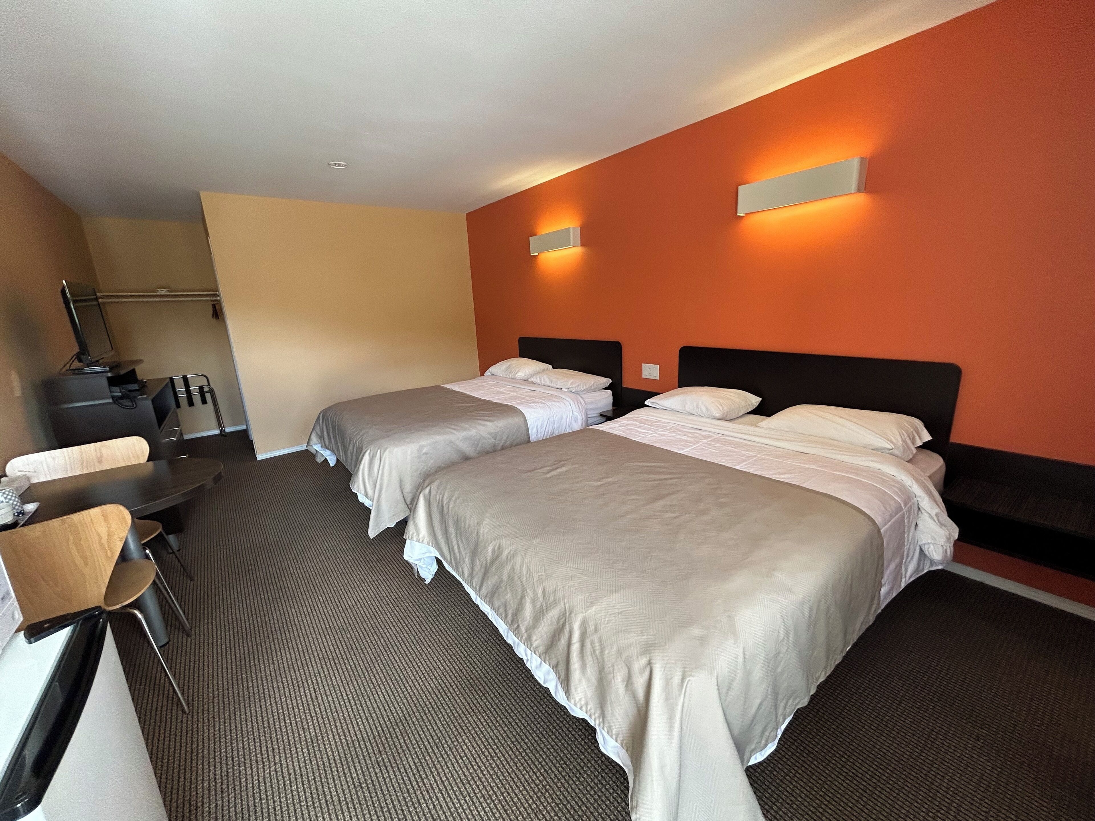 A hotel room with two beds, a desk, and a chair.