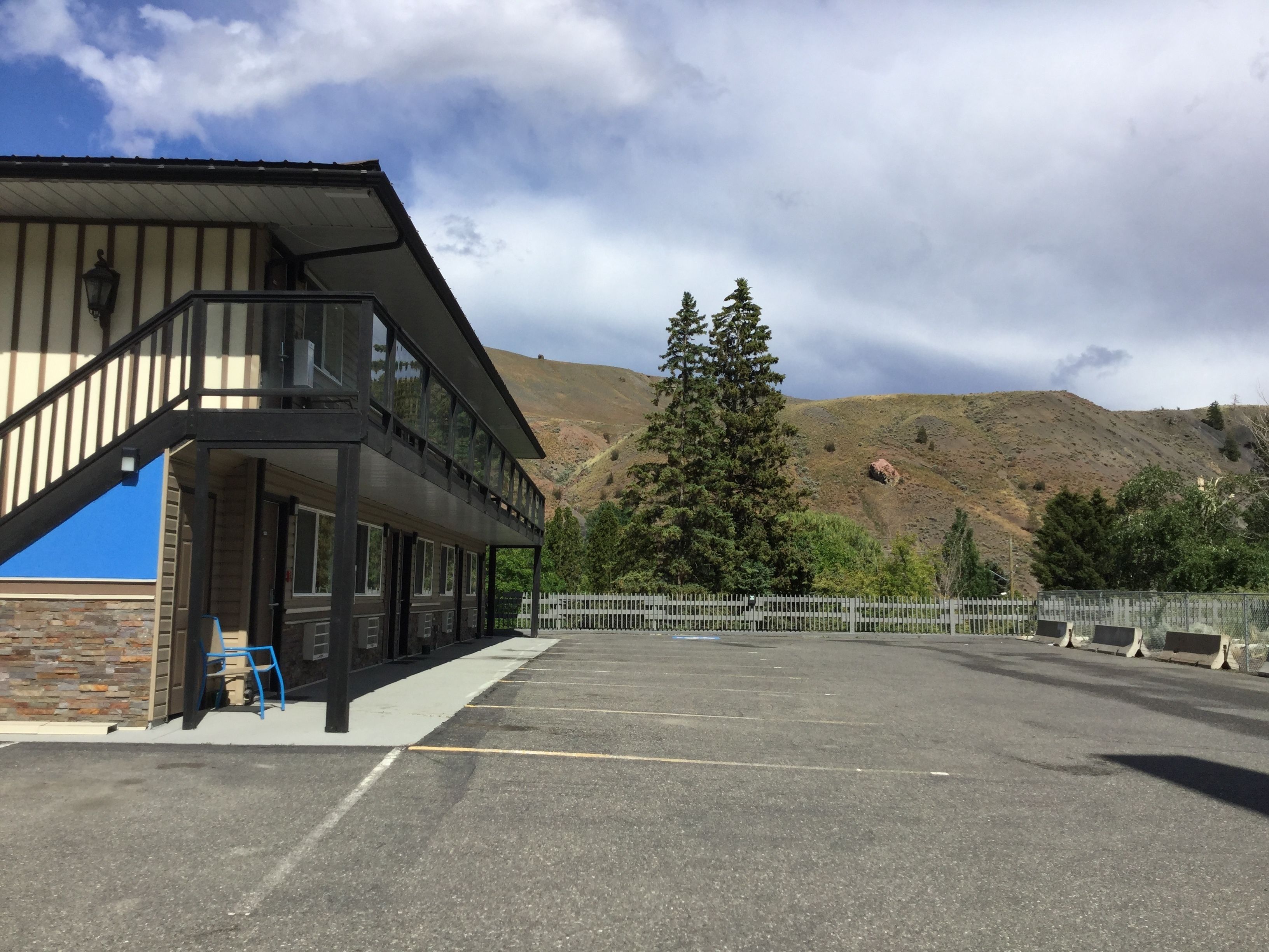 A building with a balcony, a parking lot, and a mountainous backdrop.
