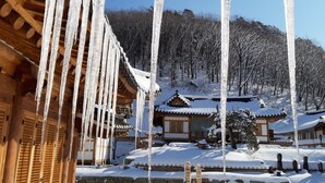 A traditional wooden building with a snow-covered courtyard and icicles hanging from the roof. - Korea Palace Hotel (Pyeongchang)