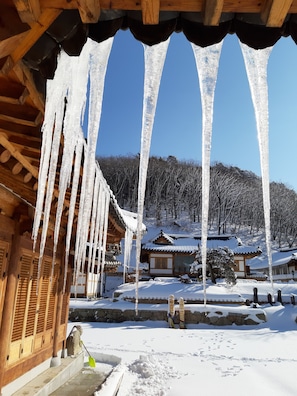 Traditional building with a distinctive architectural style, featuring vertical wooden beams and a sloped roof, set amidst a serene winter landscape.
