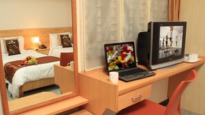 A hotel room with a bed, a desk with a laptop and a television, and a mirror. - Hoppers Stop Yelahanka (Bengaluru)