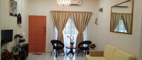 A living room with a sofa, two chairs, a coffee table, a chandelier, and a door.