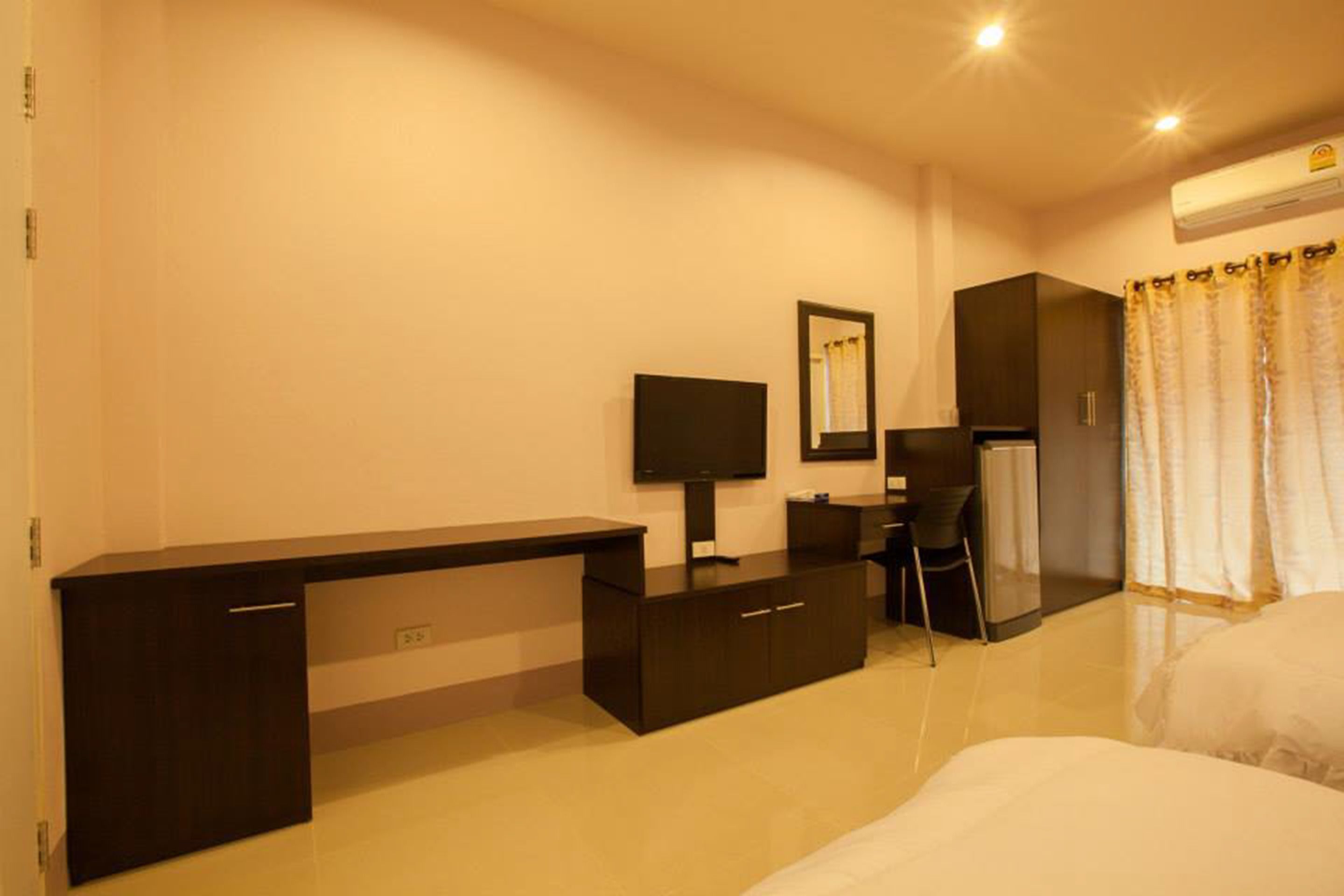 Une chambre d’hôtel comprenant un lit, un bureau avec une chaise, une télévision et une armoire.