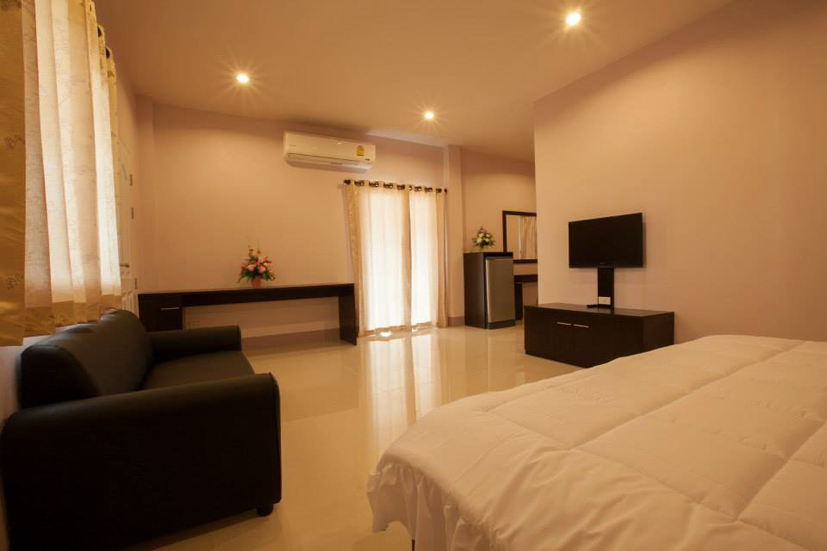 Habitación de hotel con cama, sofá, televisión, escritorio y aire acondicionado.
