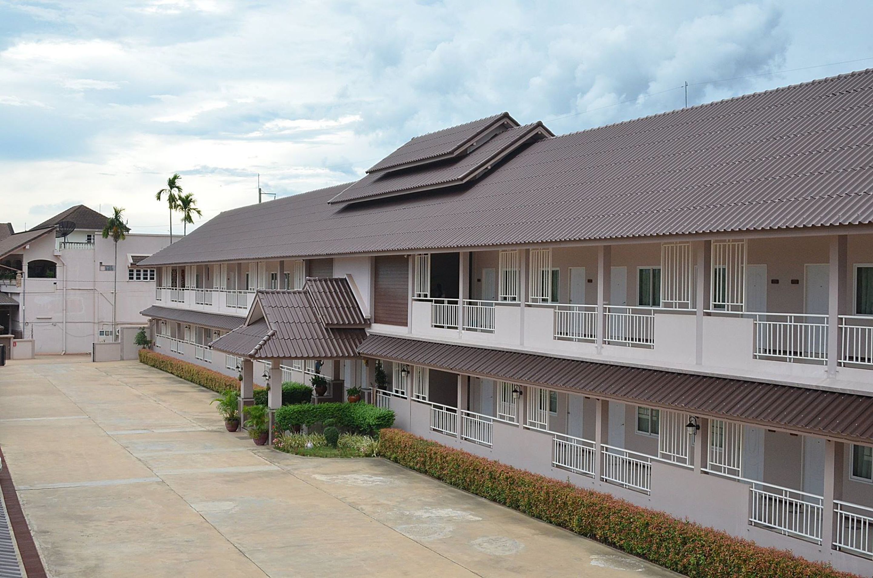 A multi-story hotel with a flat roof, balconies, and a covered walkway.