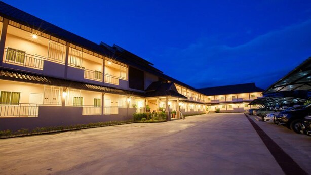 A hotel with multiple floors, a covered parking area, and a well-lit exterior at dusk. - Chiang Kham Grand Villa (Chiang Kham)