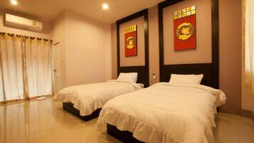 A hotel room with two beds, a window with curtains, and wall decorations.