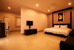 Habitación de hotel con una cama grande, una mesita de noche, un televisor de pantalla plana y una obra de arte colgada en la pared.