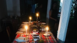 Ein Esstisch, gedeckt für eine Mahlzeit, mit mehreren Gerichten und Kerzen.