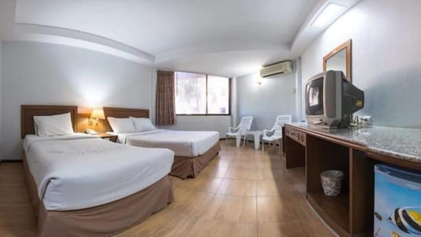 Une chambre d’hôtel avec deux lits, un bureau avec une télévision, une chaise et une fenêtre.