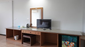 Une pièce comprenant un bureau en bois, une télévision, un miroir et un petit aquarium.