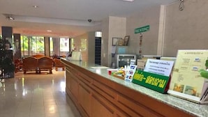 Un espace d’accueil avec un comptoir, un panneau indiquant que l’accès à Internet est gratuit, et une brochure présentant les tarifs des chambres.