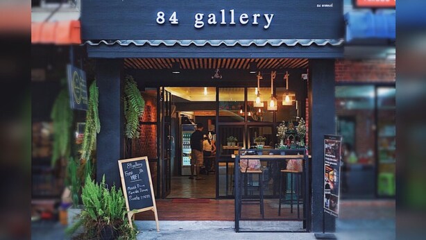 The exterior of 84 Gallery, featuring a modern storefront with a signboard advertising free WiFi, mixed dorm, female dorm, and private rooms. - 84 Gallery - Hostel (Chiang Mai)