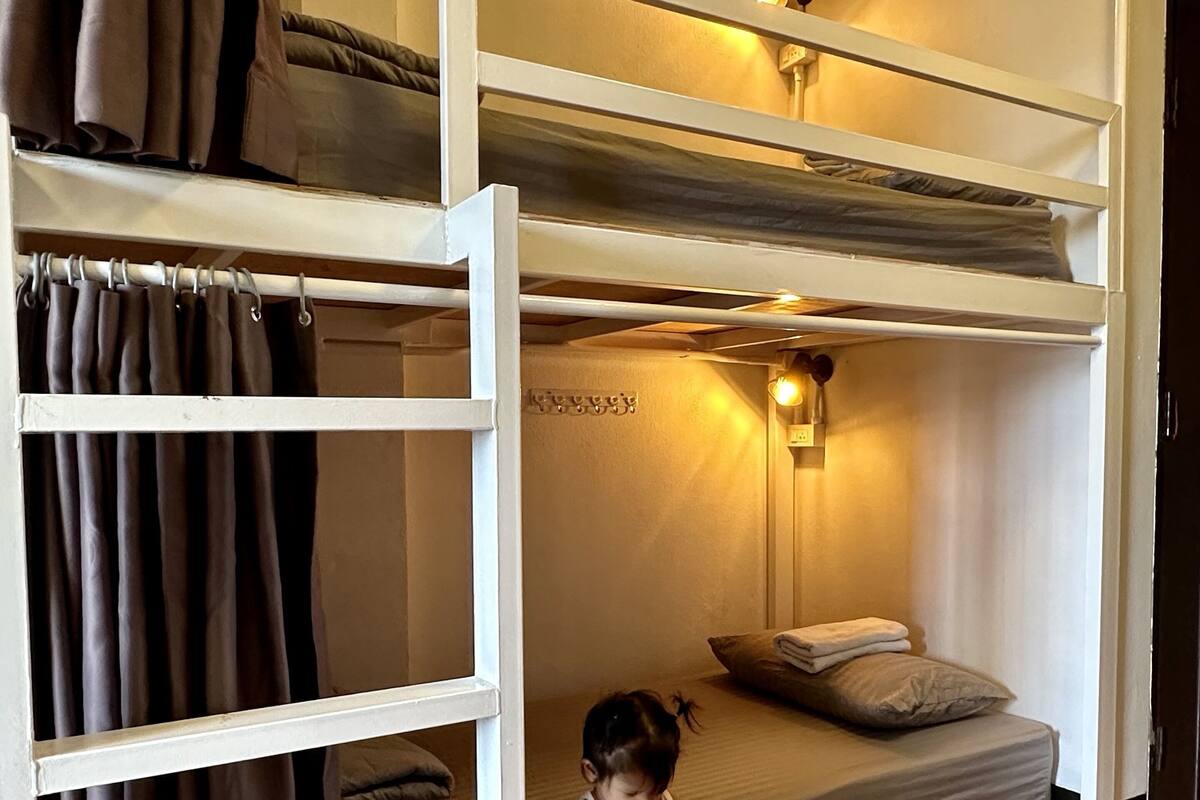 A bunk bed room with a child sitting on the lower bunk.