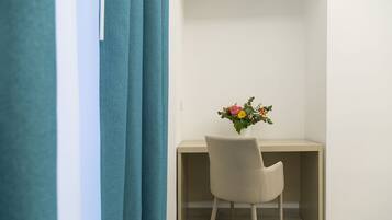 Una habitación con escritorio, silla y un jarrón de flores.