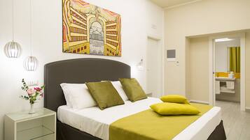 Un dormitorio moderno con cama, mesitas de noche, un cuadro y un baño visible a través de una puerta abierta.