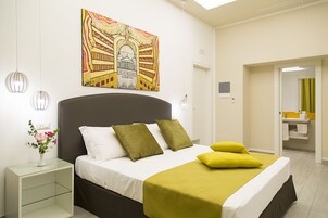 Una camera da letto moderna con un letto, comodini, un quadro e un bagno visibile attraverso una porta aperta.