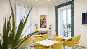 A dining area with yellow chairs and tables, a fireplace, and a large window with a view. - The Five Rooms Napoli (Naples)