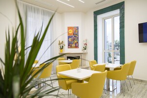 A dining area with yellow chairs and tables, a fireplace, and a large window with a view.