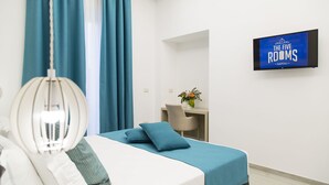 A hotel room with a bed, a desk, and a TV displaying "The Five Rooms Napoli". - The Five Rooms Napoli (Naples)