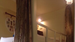 A bunk bed room with a wooden ladder, a small bedside table with a lamp, and a wall decoration. - Smile Capsule Hostel (Chiang Mai)