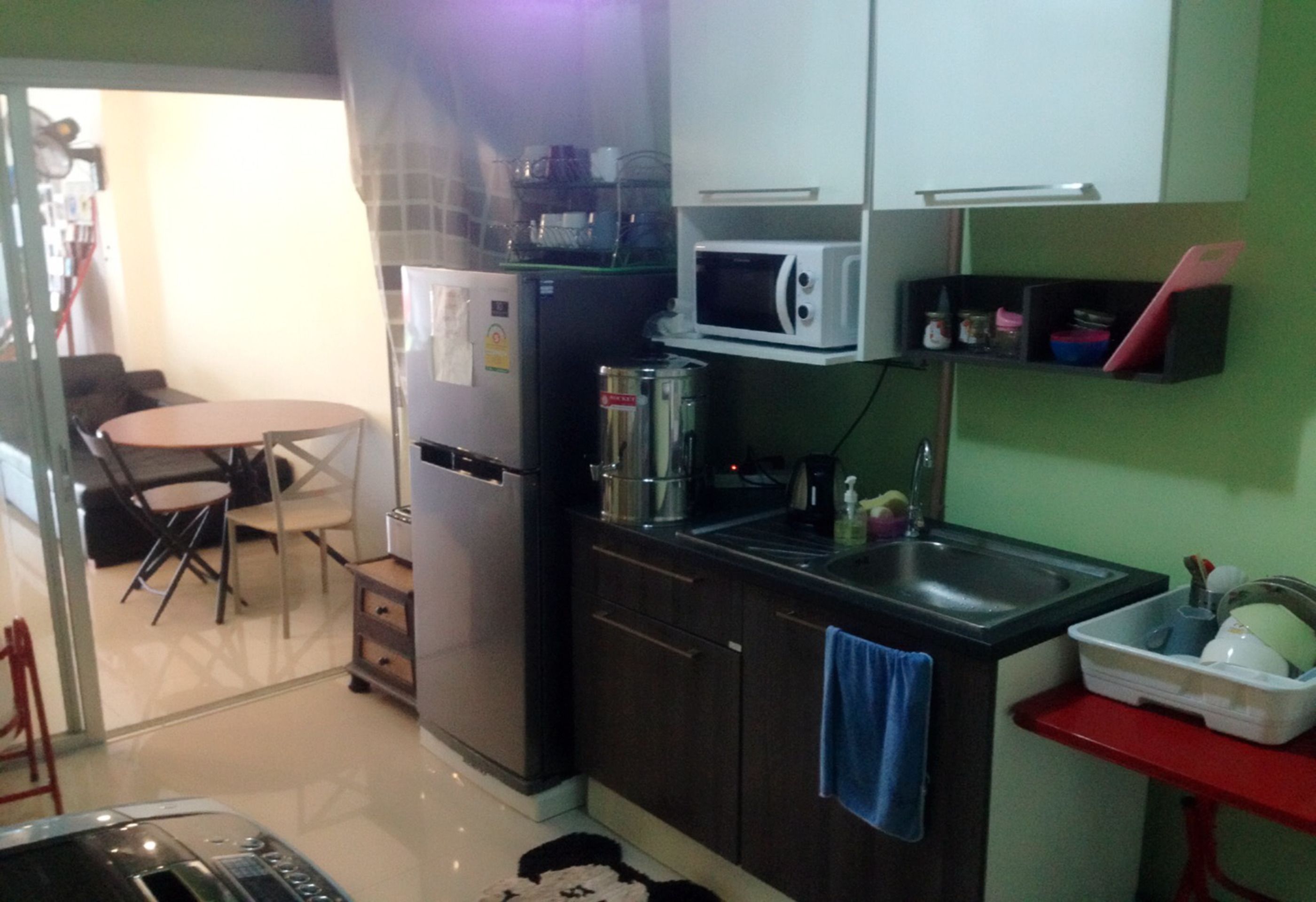 A compact kitchen with a refrigerator, microwave, sink, and a dining area with a table and chairs.