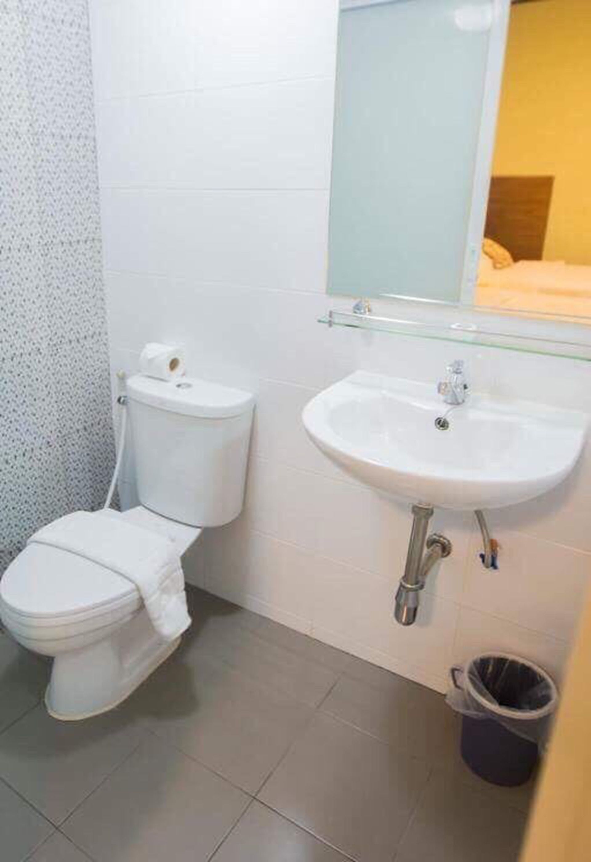A small bathroom with a toilet, sink, and mirror.