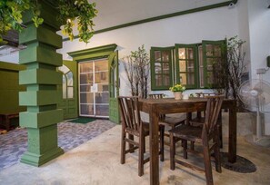 A dining area with a wooden table and chairs, a green door, and a fan. - iRoom Boutique House (Chiang Mai)