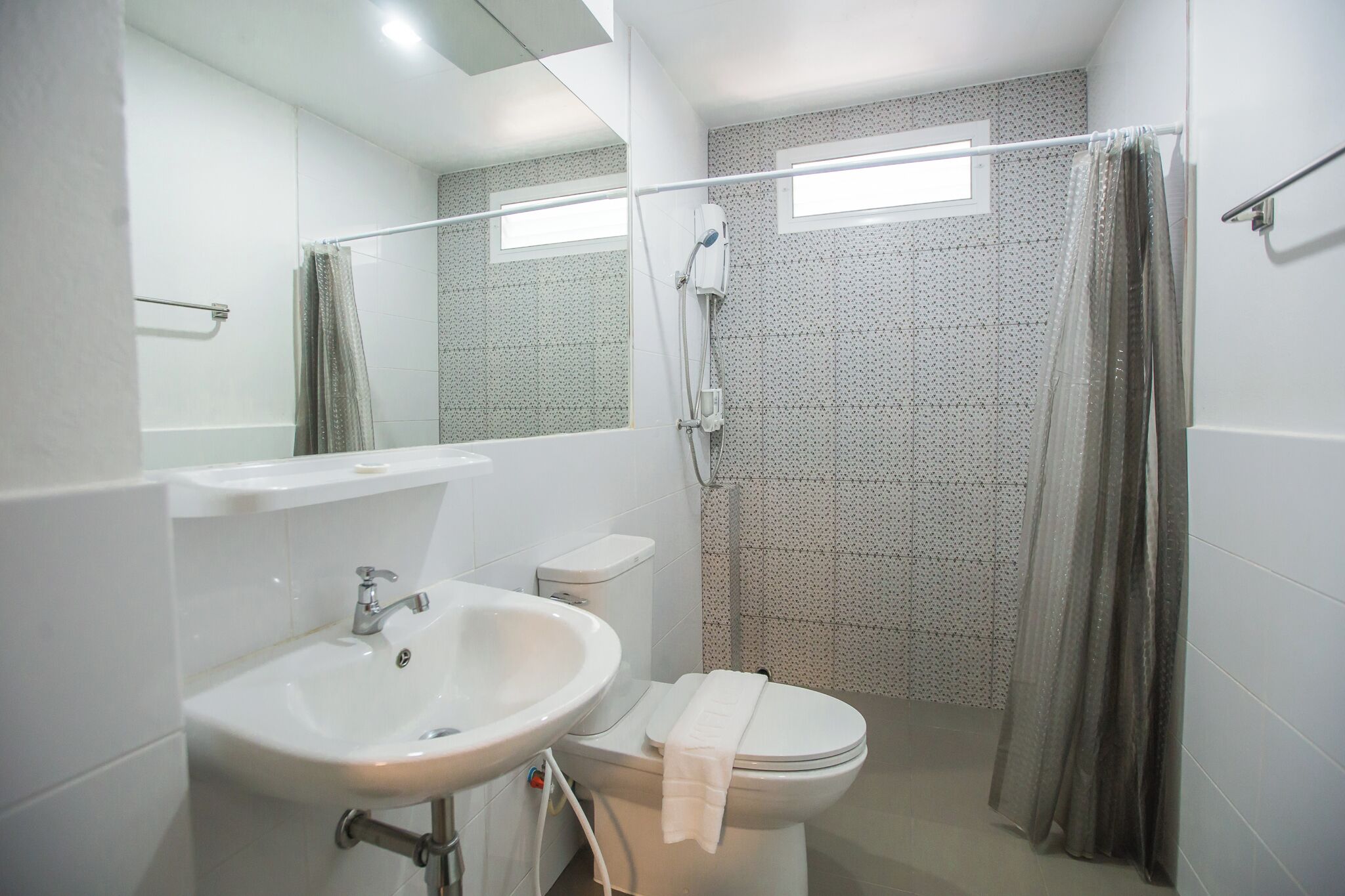Un baño con lavamanos, inodoro y zona de ducha blanca.