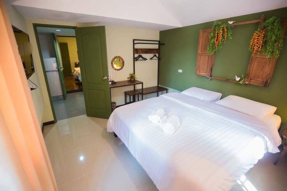 A hotel room with a bed, a desk, and a mirror.