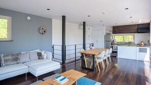 A modern living room with a white sofa, a wooden coffee table, and a dining area with a wooden table and chairs. - Forest Hideaway (Niseko)