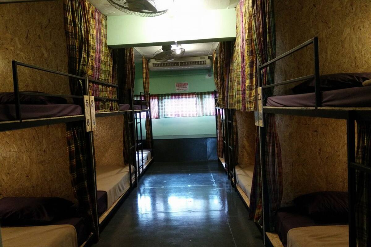 A dormitory room with bunk beds, a fan, and a window with curtains.