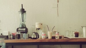 En køkkenbordplade med en blender, kaffemaskine og forskellige glasbeholdere.