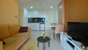 A modern living room with a sofa, a coffee table with flowers, a TV, and a kitchen in the background. - Paradise Park (Pattaya)