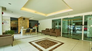 A modern hotel lobby with a reception desk, seating area, and a large glass door leading outside. - Paradise Park (Pattaya)
