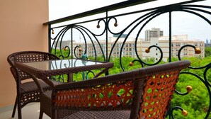 A balcony with wicker furniture and a glass table, overlooking a cityscape. - Paradise Park (Pattaya)