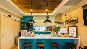 A kitchen with a central island, bar stools, pendant lighting, and a decorative sign. - Maneeya Park Residence (Bangkok)