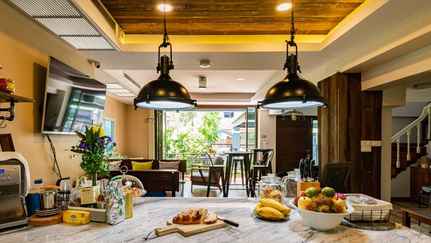 A kitchen with marble countertops, two pendant lights, a large window, and a view of the outdoors. - Maneeya Park Residence (Bangkok)