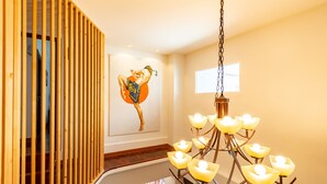 A modern interior with a wooden slat partition, a large mural of a martial artist, and a chandelier with multiple light fixtures. - Maneeya Park Residence (Bangkok)