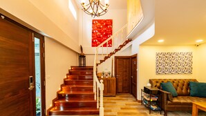 A wooden staircase leading to a second floor, a leather sofa with green cushions, and a patterned wall hanging. - Maneeya Park Residence (Bangkok)