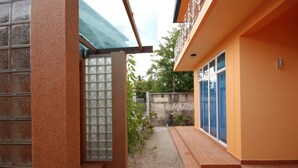 Un pasillo estrecho con suelo de baldosas, una puerta de cristal y una pared de hormigón con grafitis.