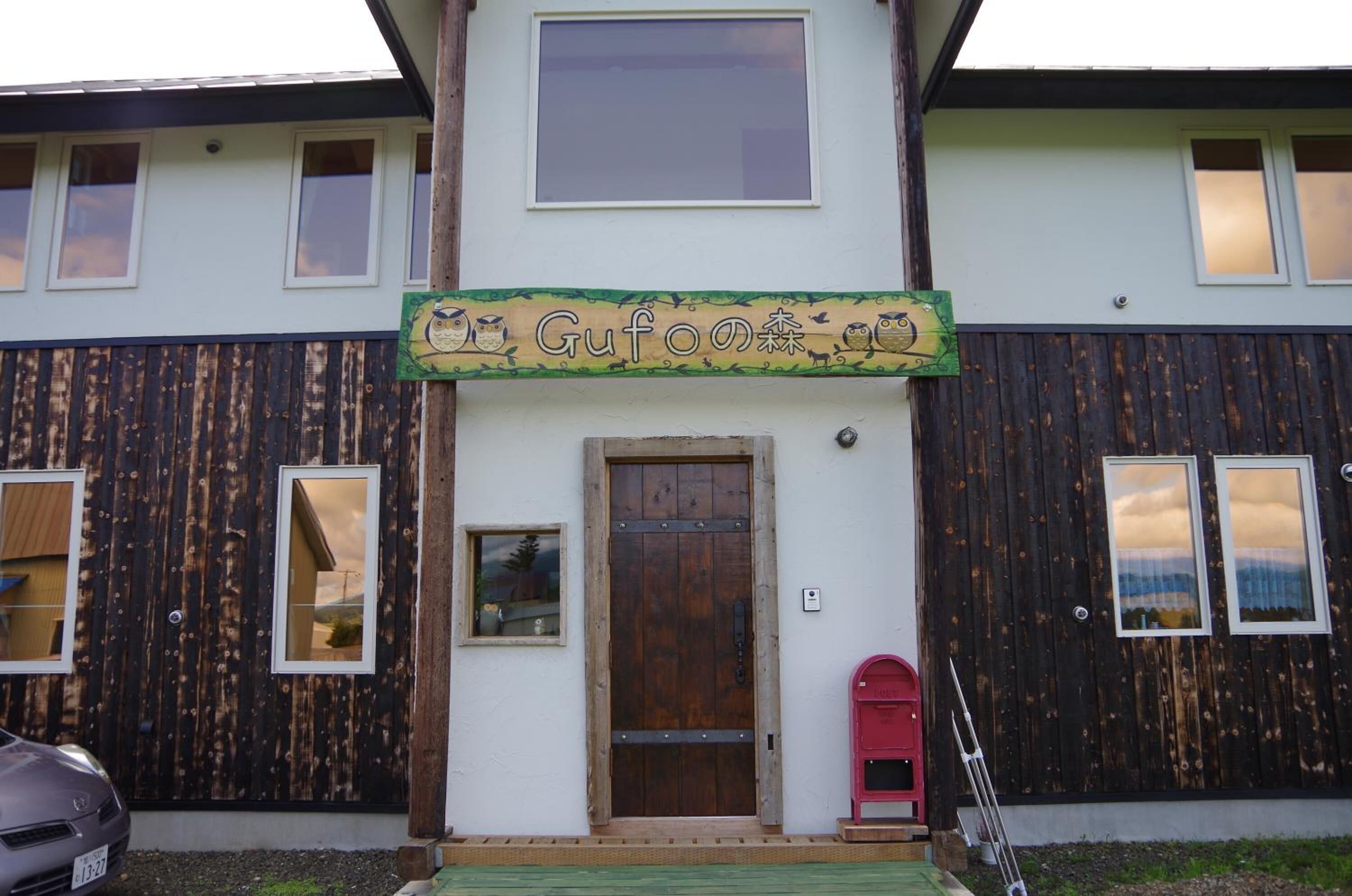 A building with a wooden facade, a central door, and a sign above the door.